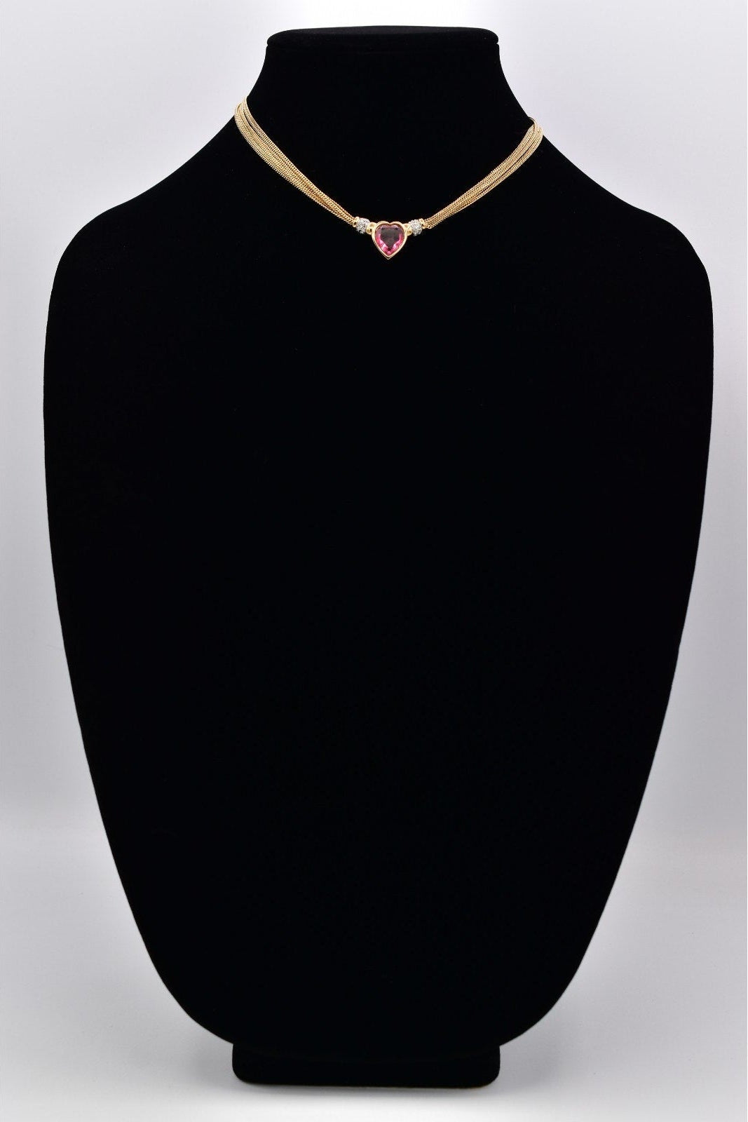 Necklace with a heart-shaped pendant on a black mannequin bust against a white background