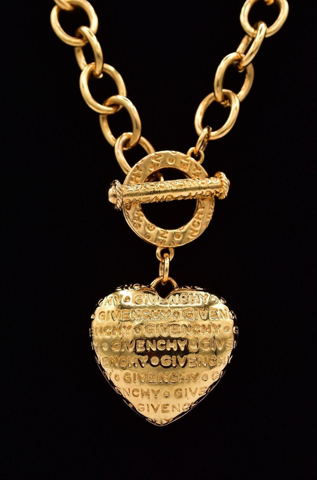 Gold necklace with a heart-shaped pendant on a black background