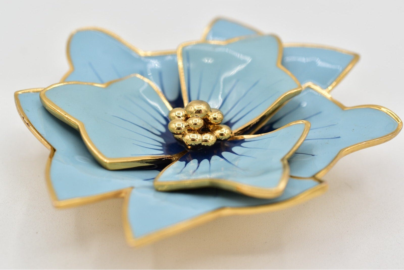 Blue flower-shaped object with gold accents on a white background