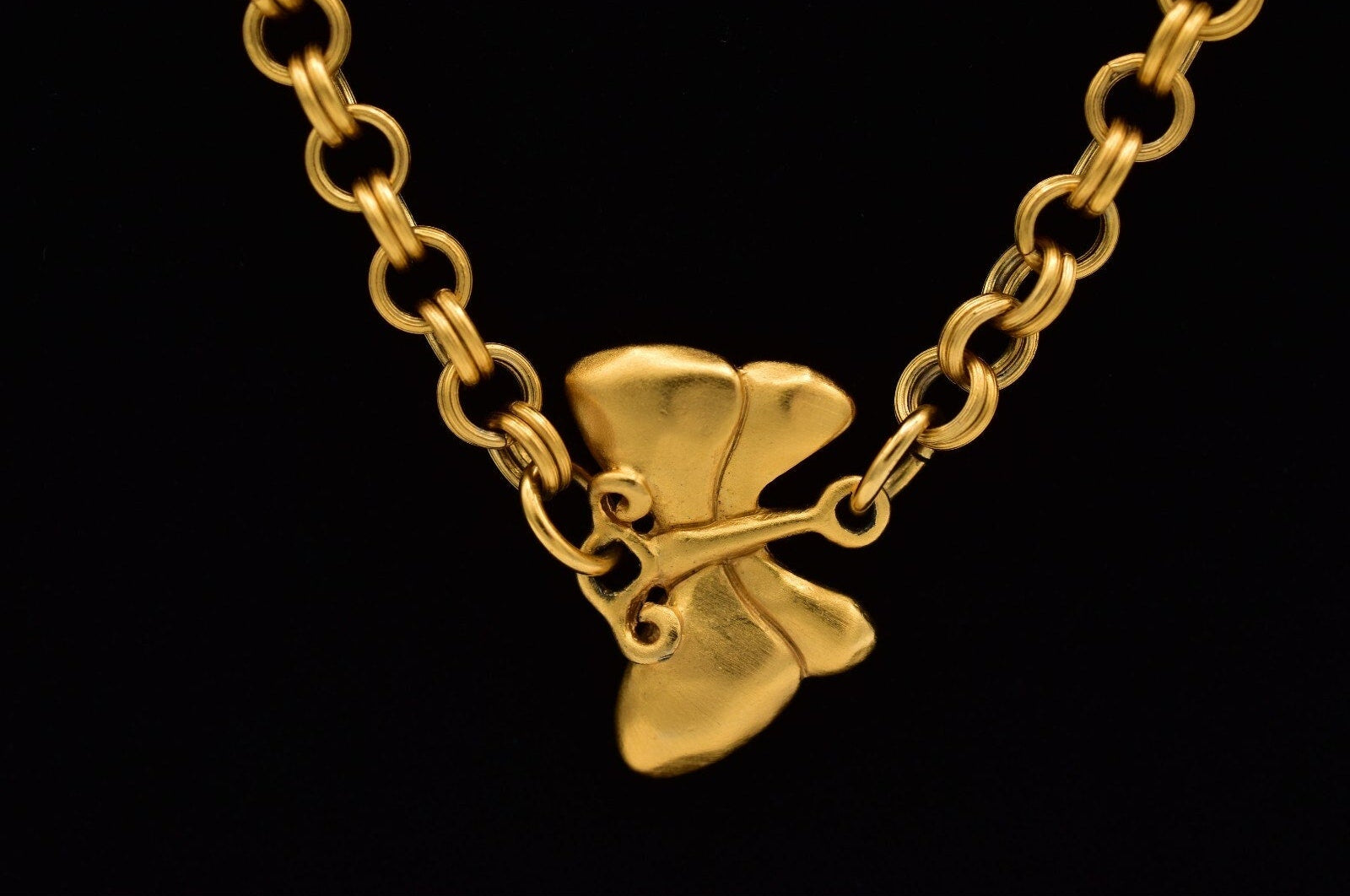 Gold necklace with a butterfly embellishment on a black background