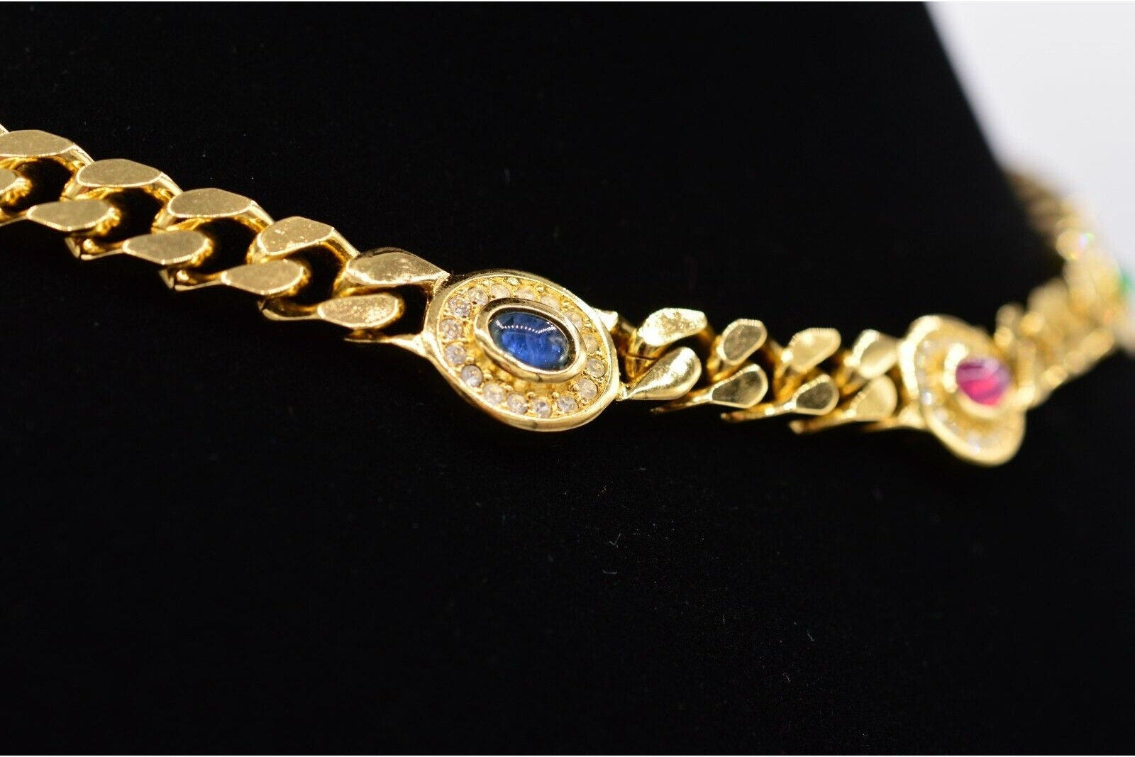 Gold necklace with gemstone accents on a black background

