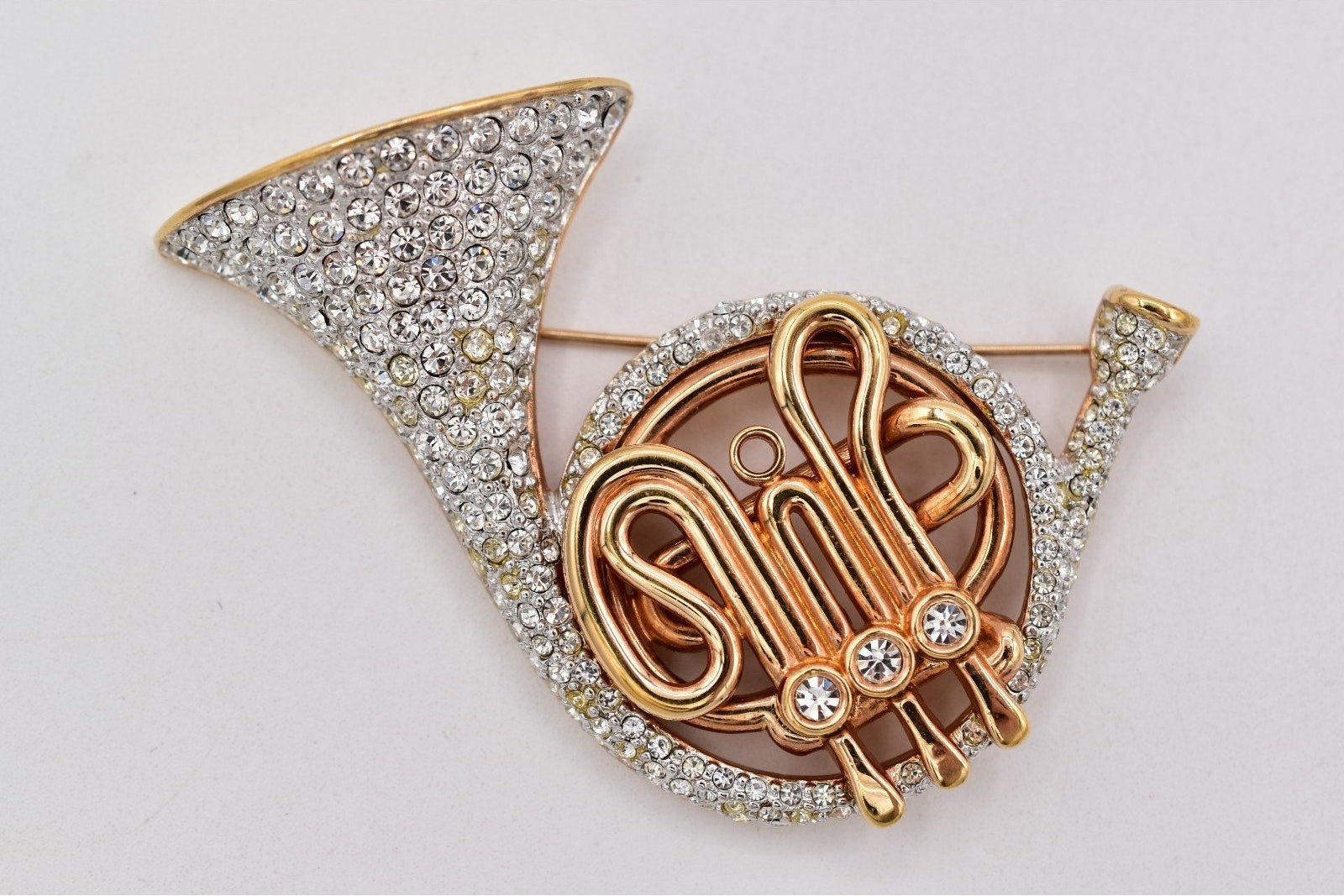 Gold and silver brooch with intricate design on a light gray background