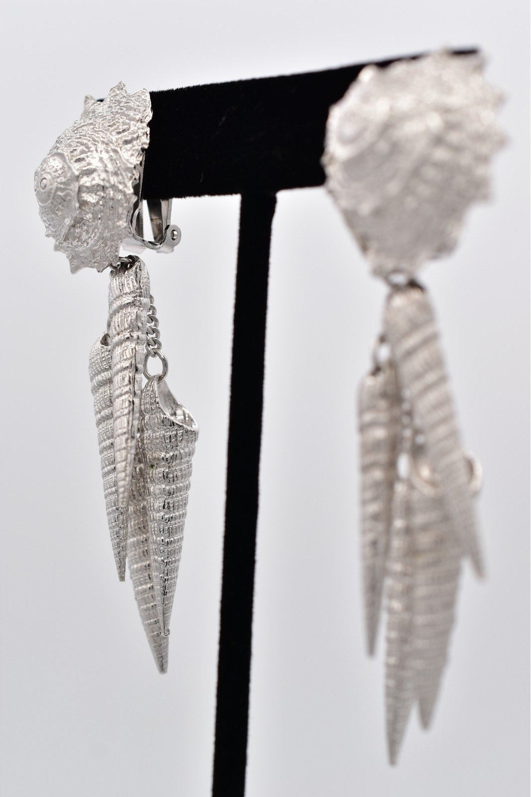 Pair of silver spike earrings on a stand with a white background