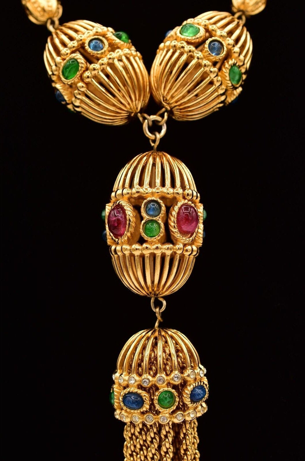 Closeup of a vintage Christian Dior gold-tone necklace featuring red, blue, and green cabochons with a tassel.