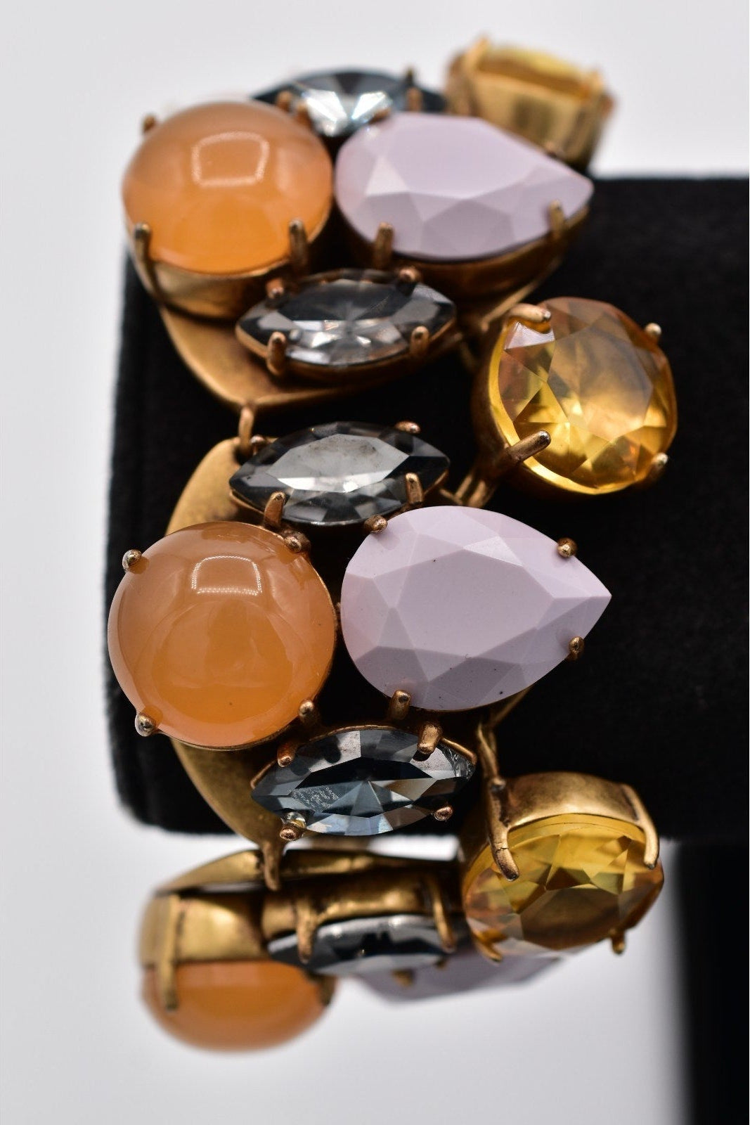 Multicolored gemstone bracelet on a black stand with a white background