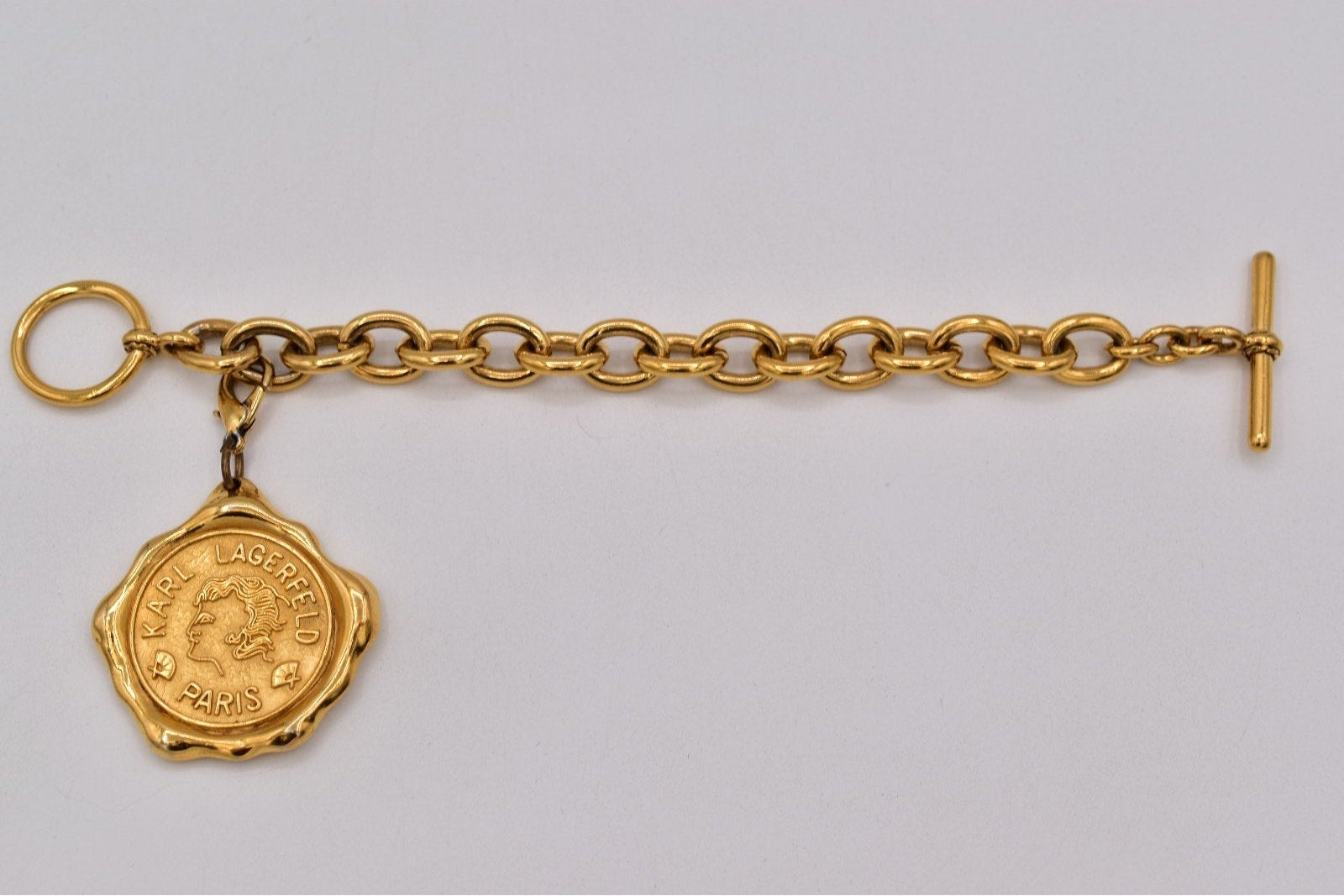Gold chain bracelet with a medallion on a gray background