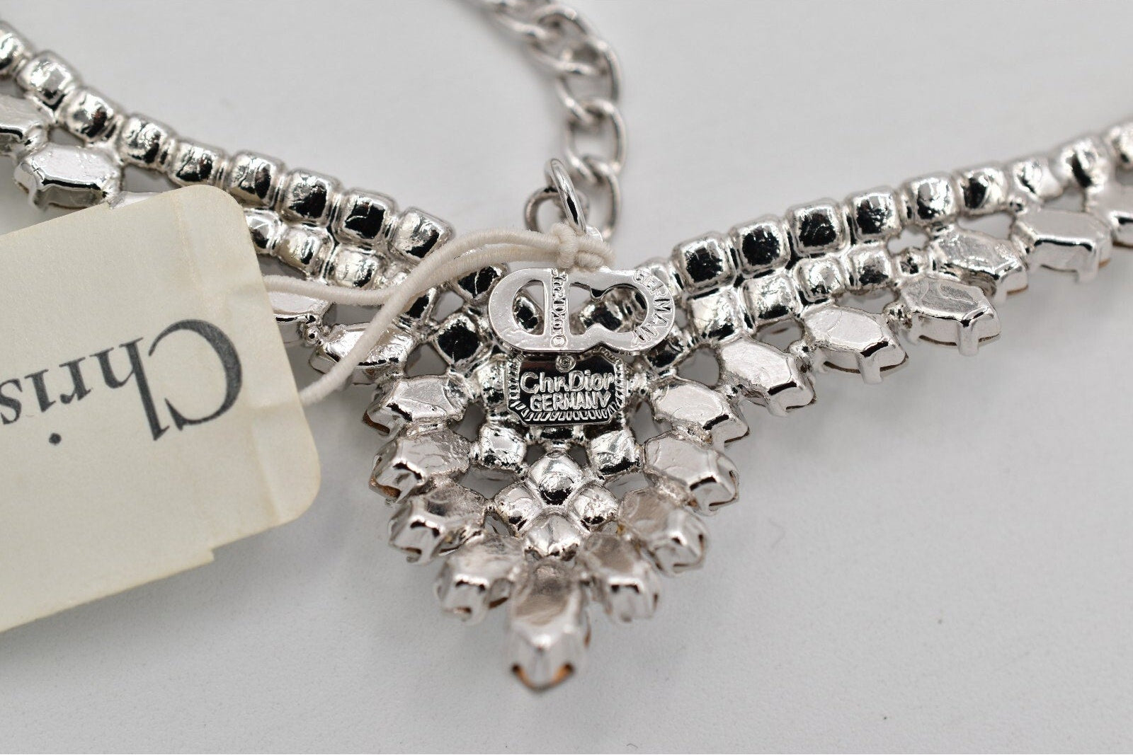 Back view of a vintage Christian Dior Germany silver necklace with a tag on a light gray background