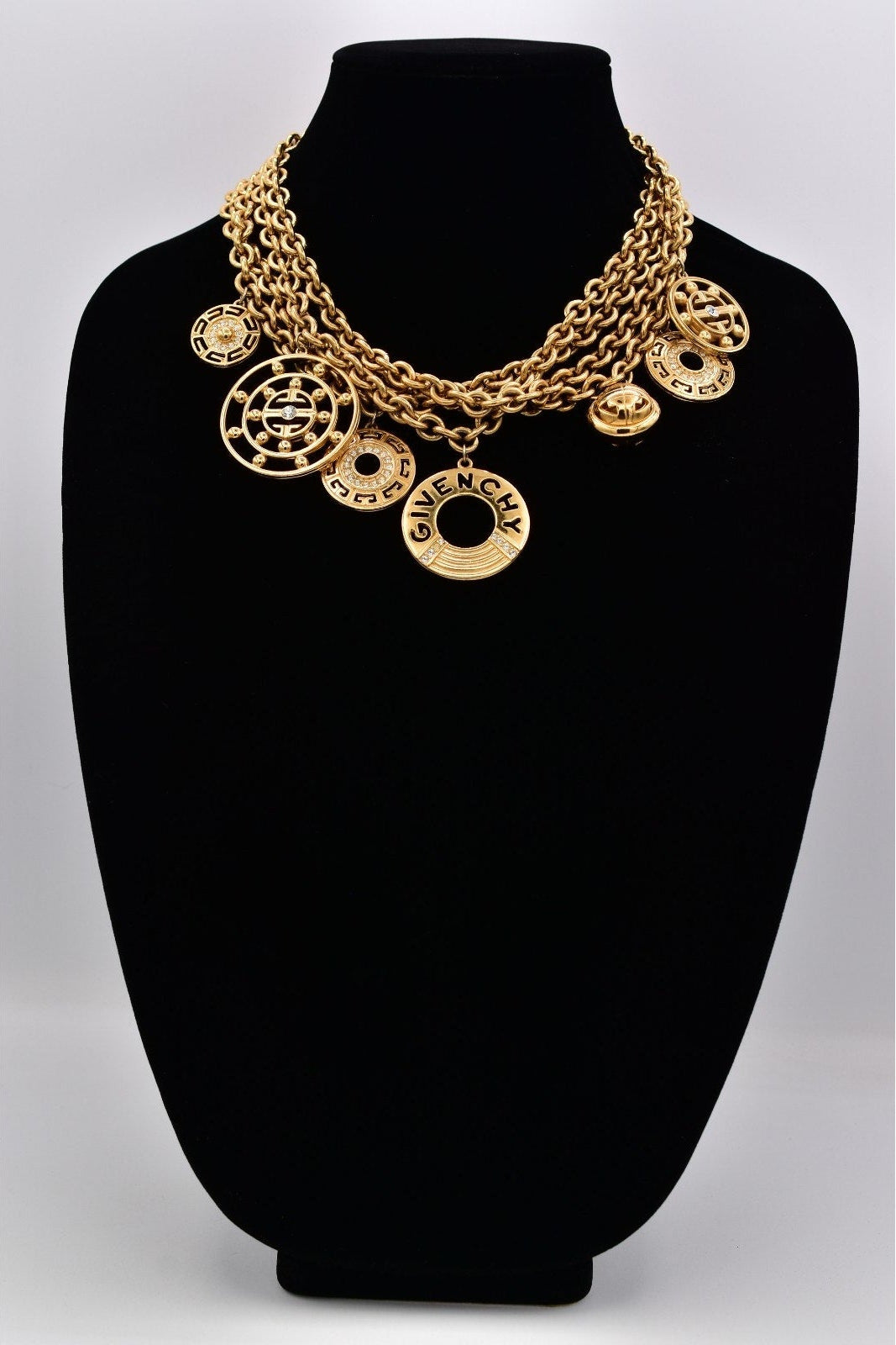 Gold necklace on a black mannequin bust with a white background
