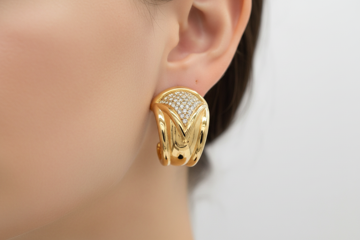 Gold hoop earrings with a clear gemstone on a white background