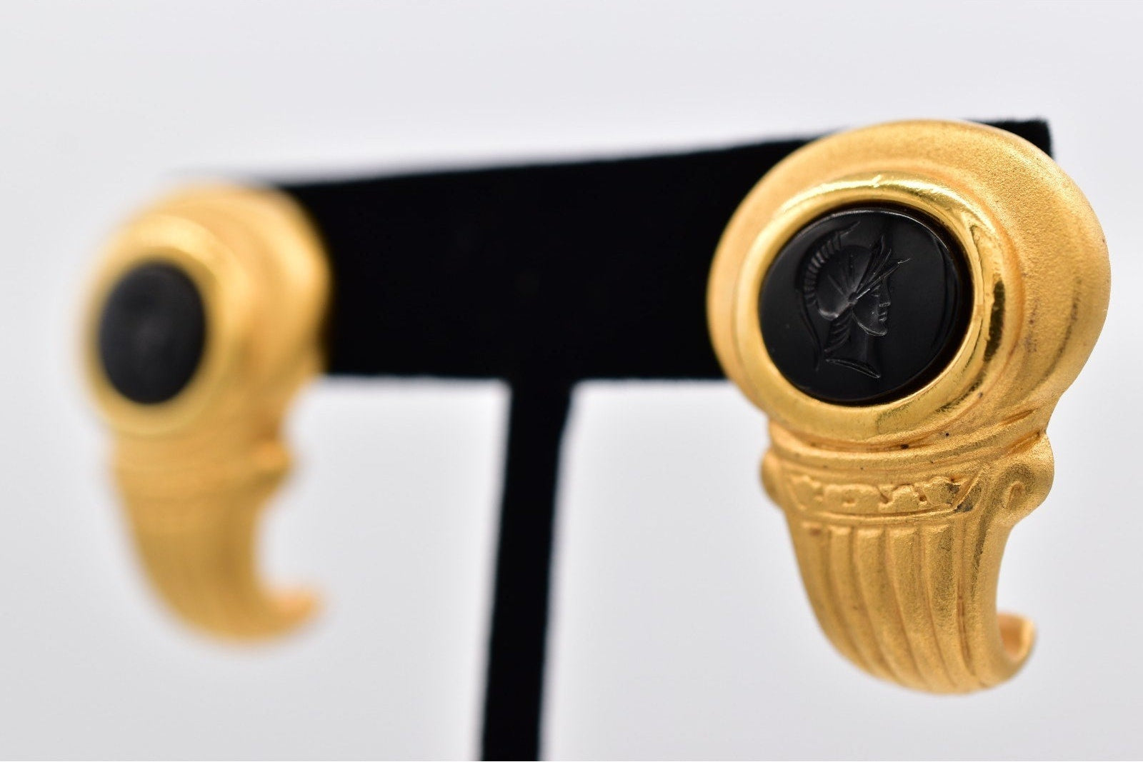 Gold earrings with black stones on a white background