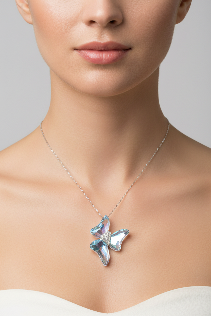 A close-up of a model wearing a delicate silver chain necklace with a butterfly-shaped pendant. The pendant features iridescent, color-shifting blue and purple crystals set in silver, with a small clear crystal center.