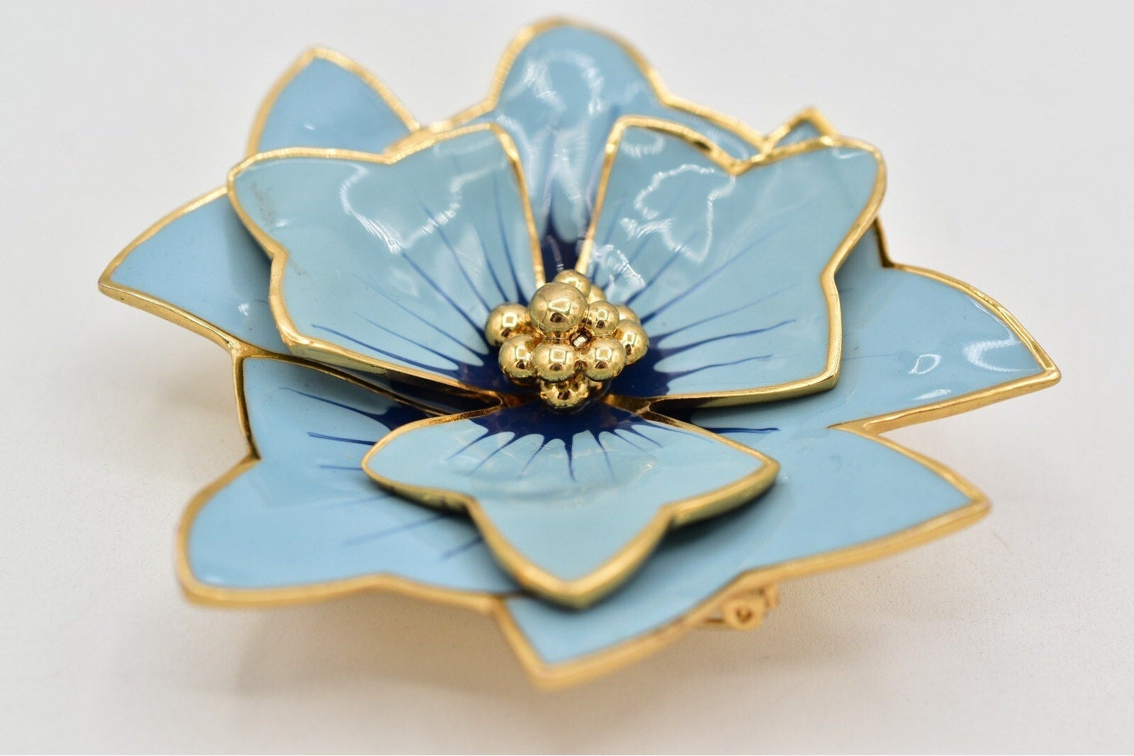 Decorative blue flower-shaped object with gold accents on a light gray background