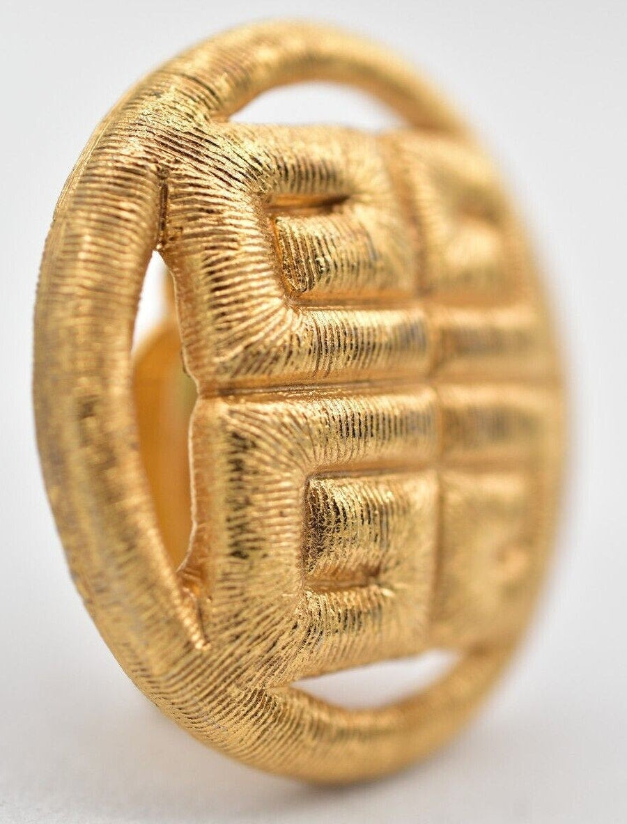 Gold earring with textured design on a light gray background