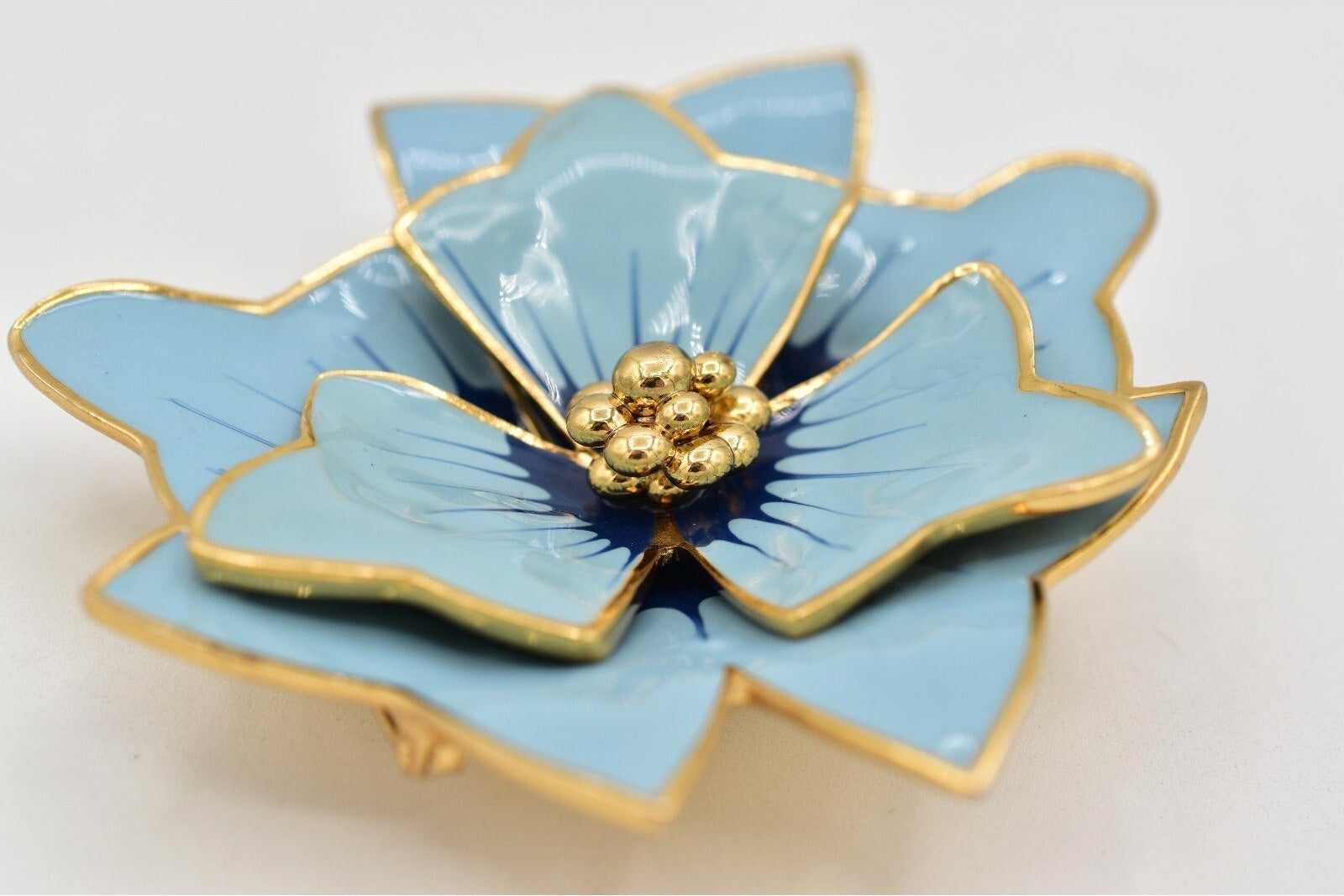 Blue flower-shaped object with gold accents on a light gray background
