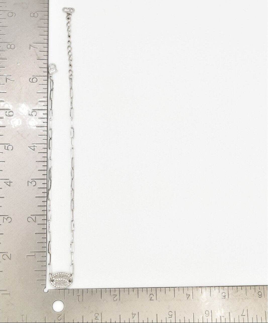 Vintage Dior J'Adore silver chain necklace with a round pendant with a ruler for scale.