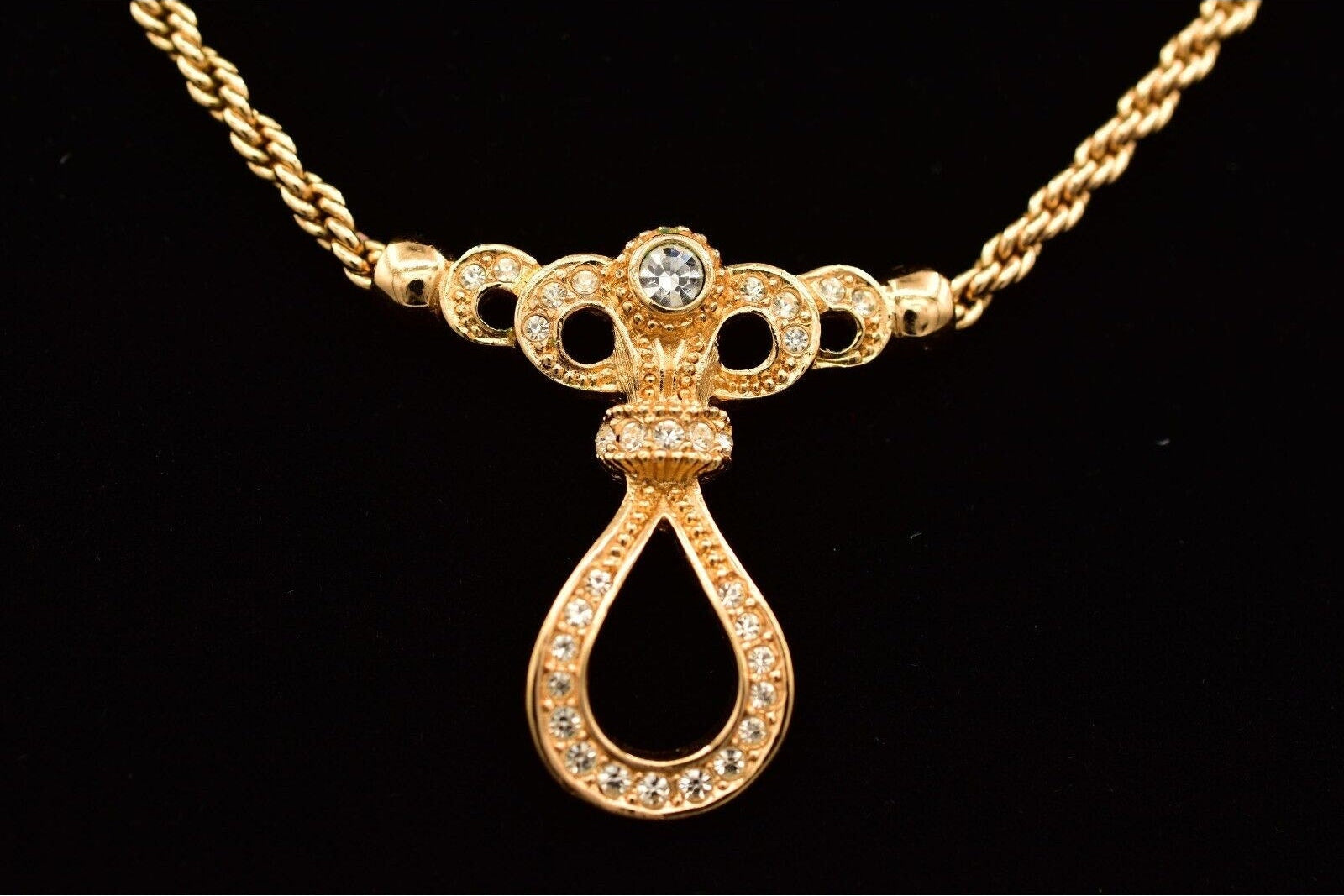 Gold necklace with a decorative pendant on a black background