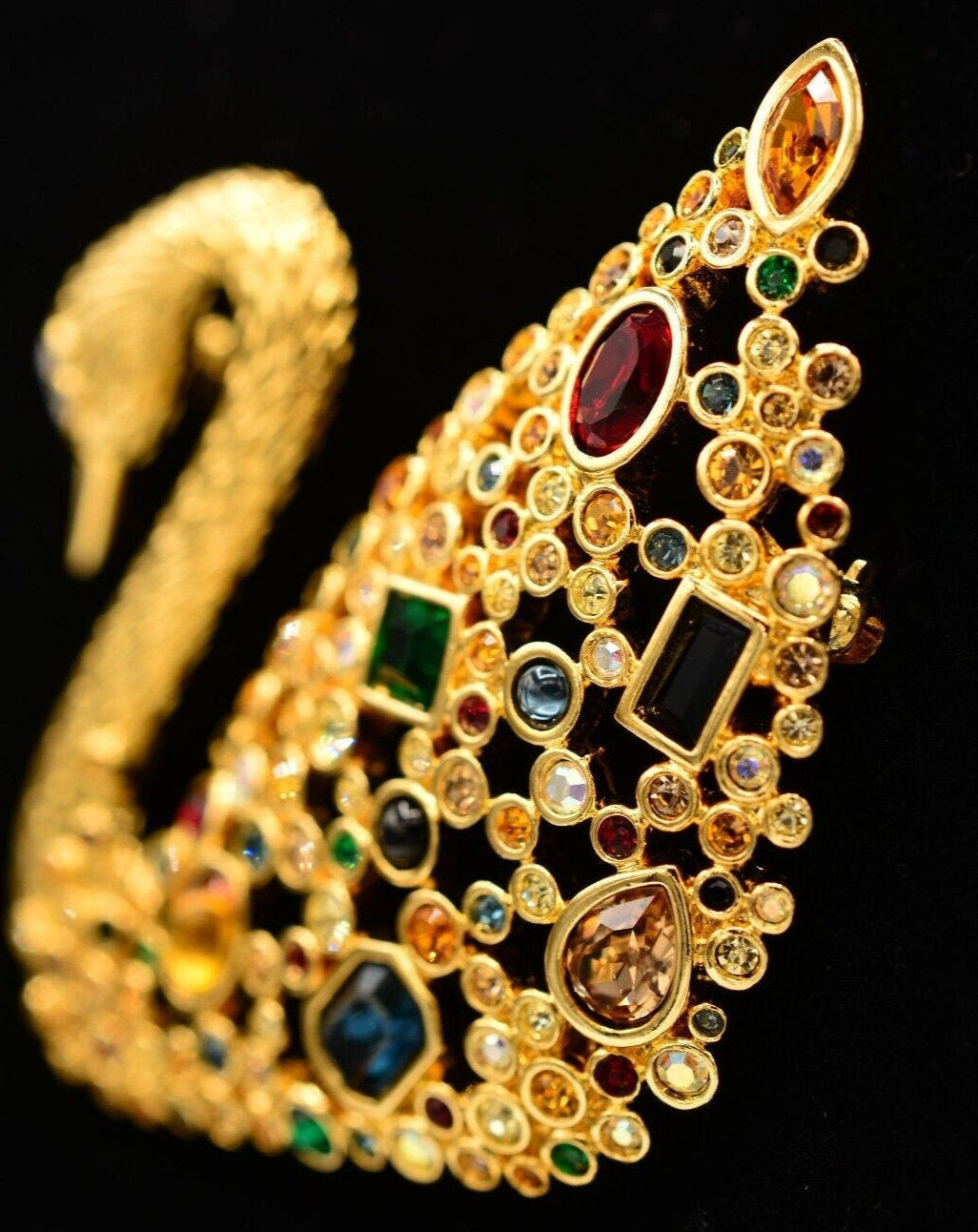 Side view of a vintage Swarovski swan brooch with multicolored rhinestone crystals on a gold-tone finish.