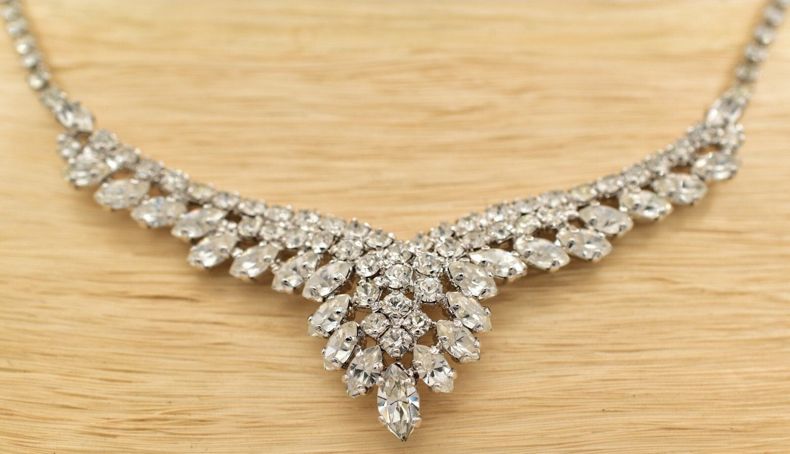 Silver necklace with clear rhinestones on a wooden surface