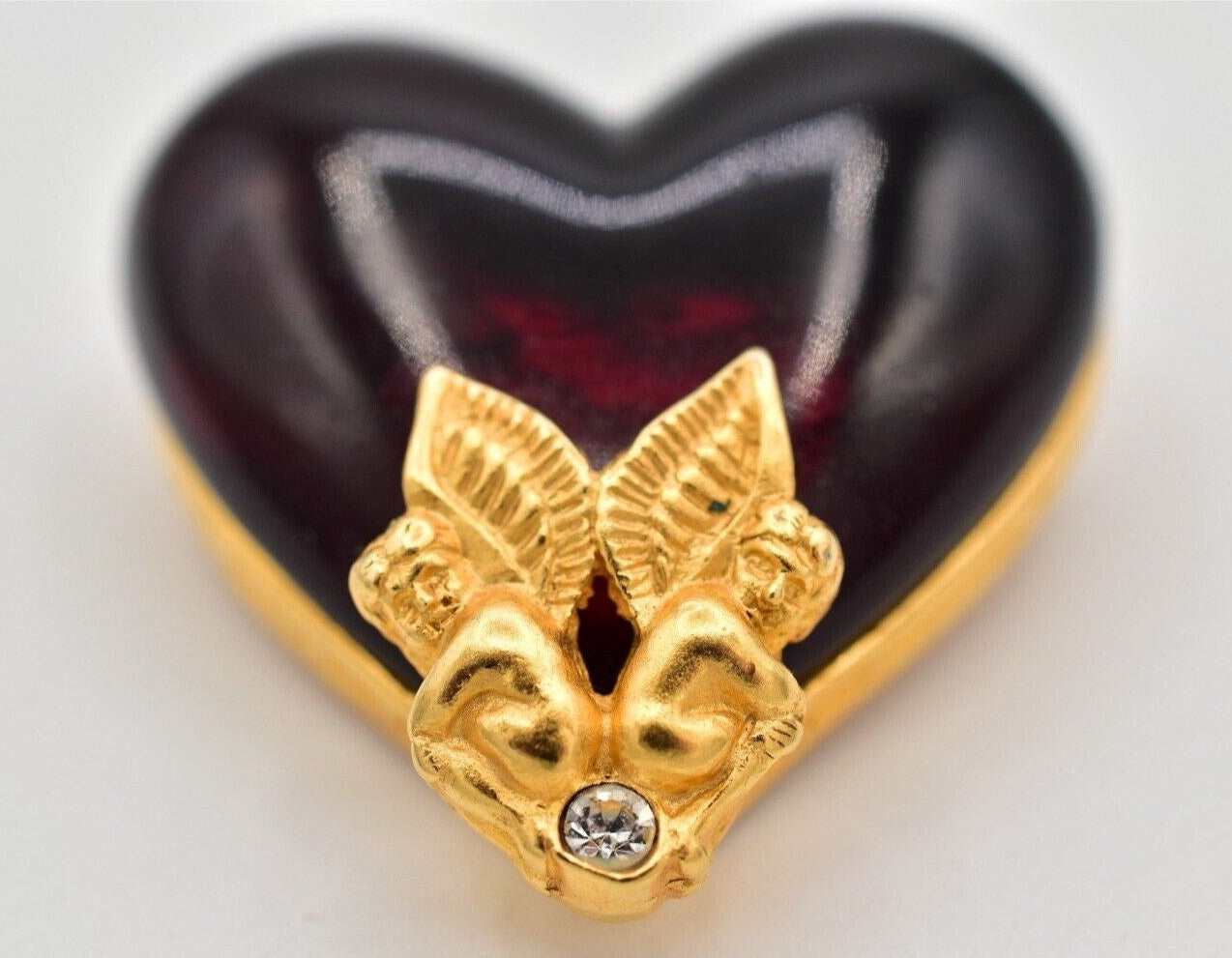 A vintage Givenchy Gripoix heart-shaped brooch with gold cherubs detail.