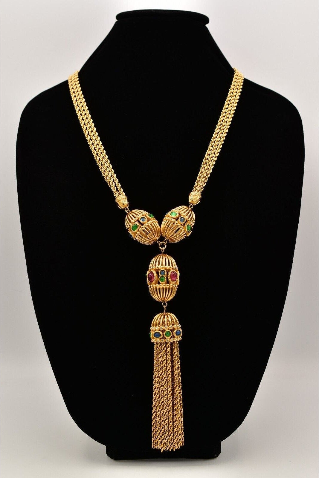 A vintage Christian Dior gold-tone necklace featuring red, blue, and green cabochons with a tassel.