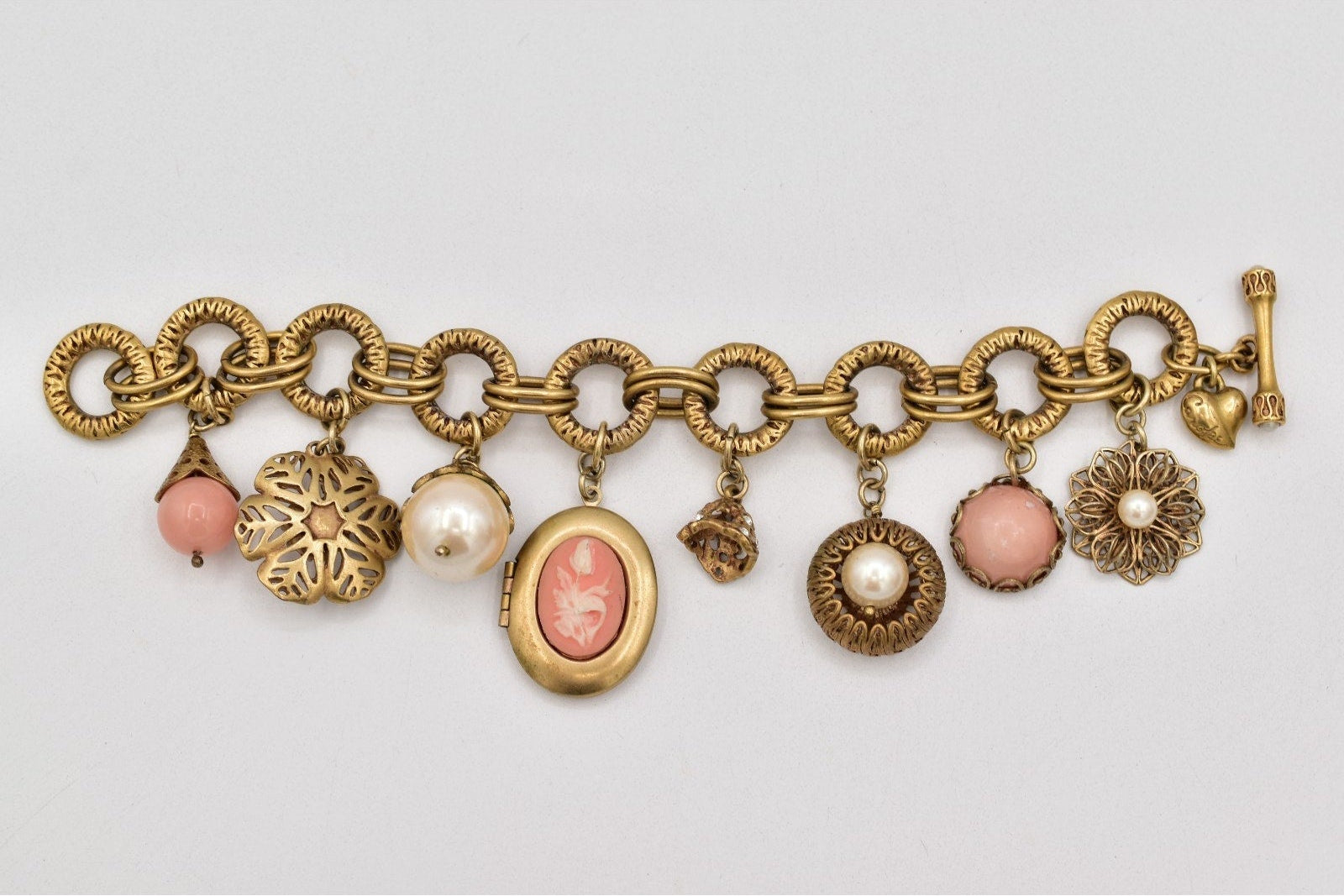 Gold charm bracelet with various charms on a light gray background