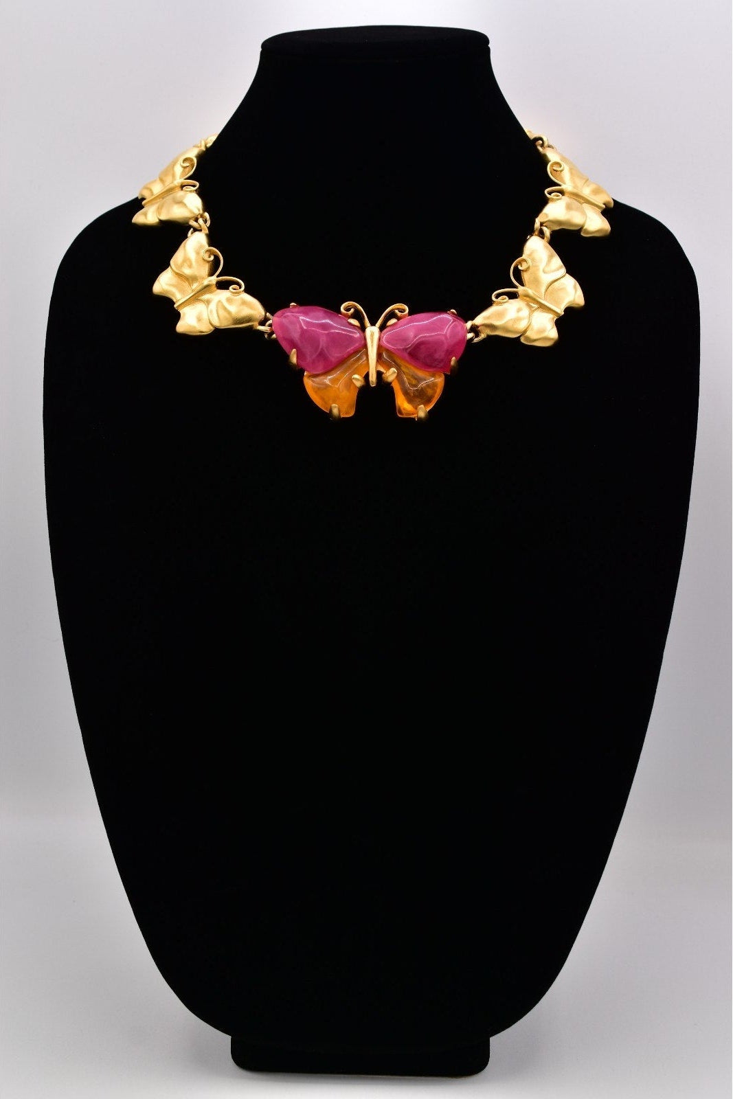 Vintage Givenchy gold butterfly necklace with pink and orange lucites on a black mannequin against a black mannequin.