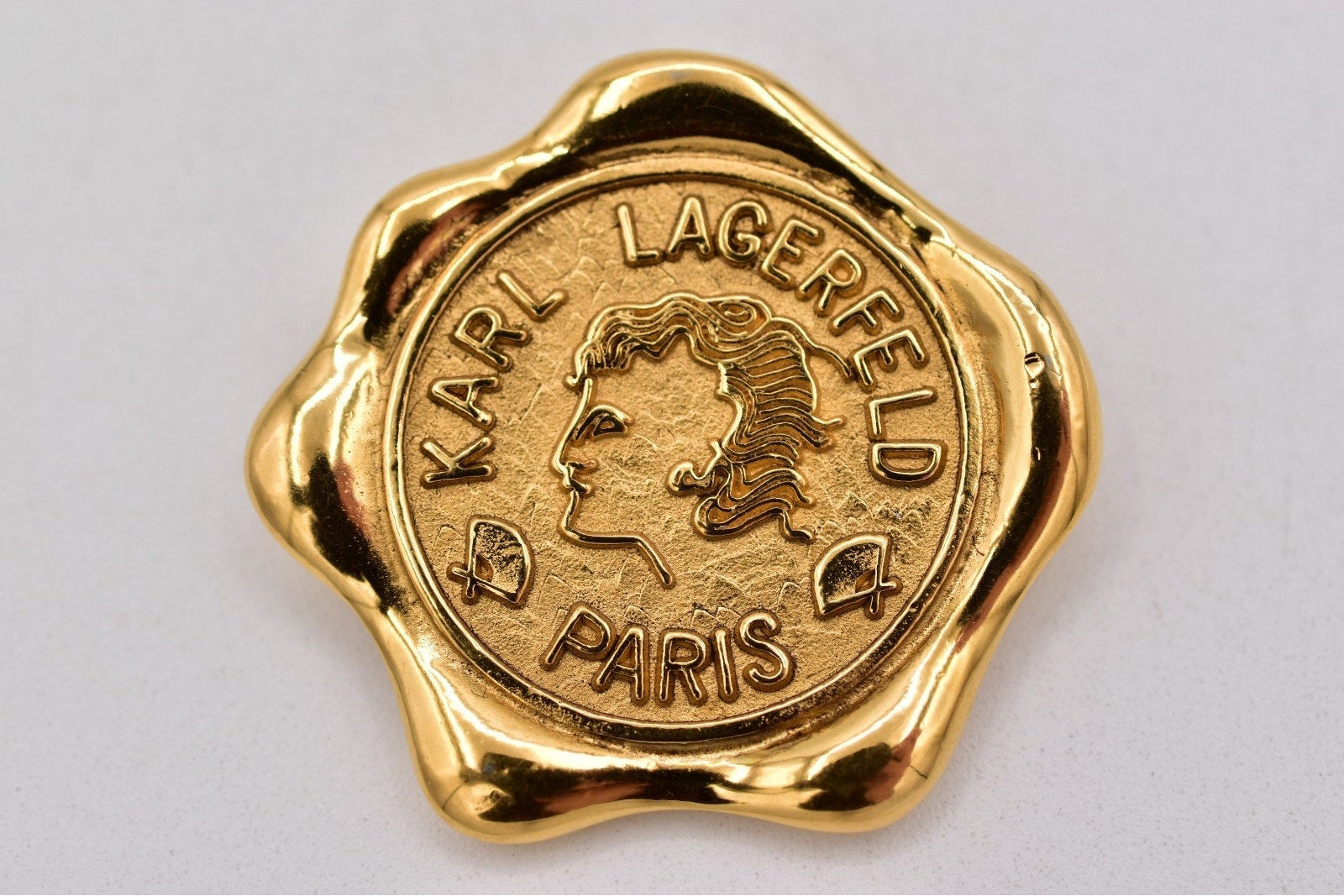 Gold wax seal stamp with 'Karl Lagerfeld Paris' text on a white background