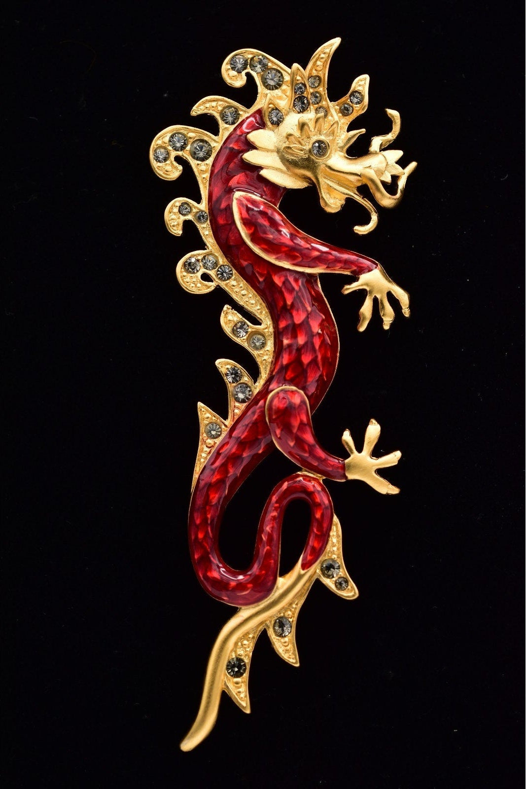 Decorative lizard-shaped object with red and gold colors on a black background