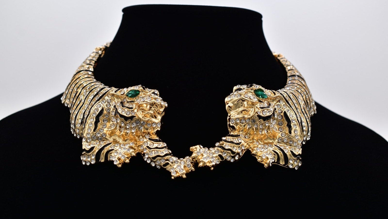 Gold lion head necklace on a black mannequin with a white background
