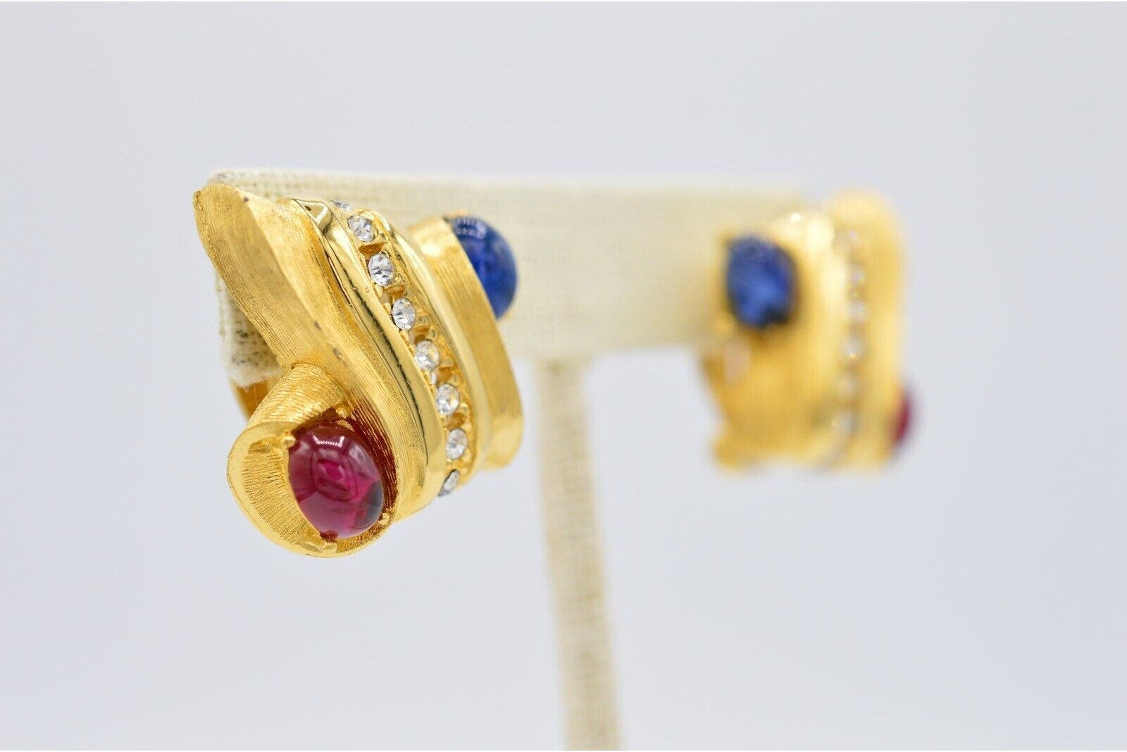 Gold earrings with gemstones on a gray background