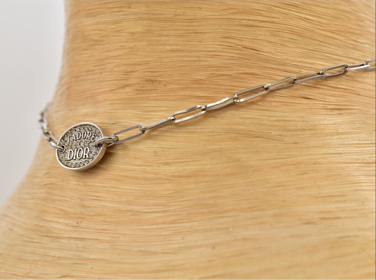 Vintage Dior J'Adore silver chain necklace with a round pendant on a wooden mannequin neck.