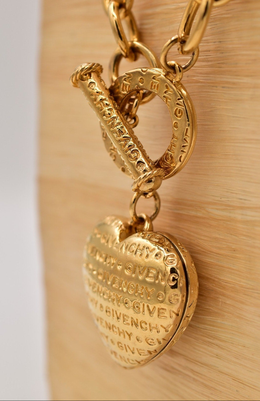 Gold Givenchy bracelet with heart-shaped charm on a beige background