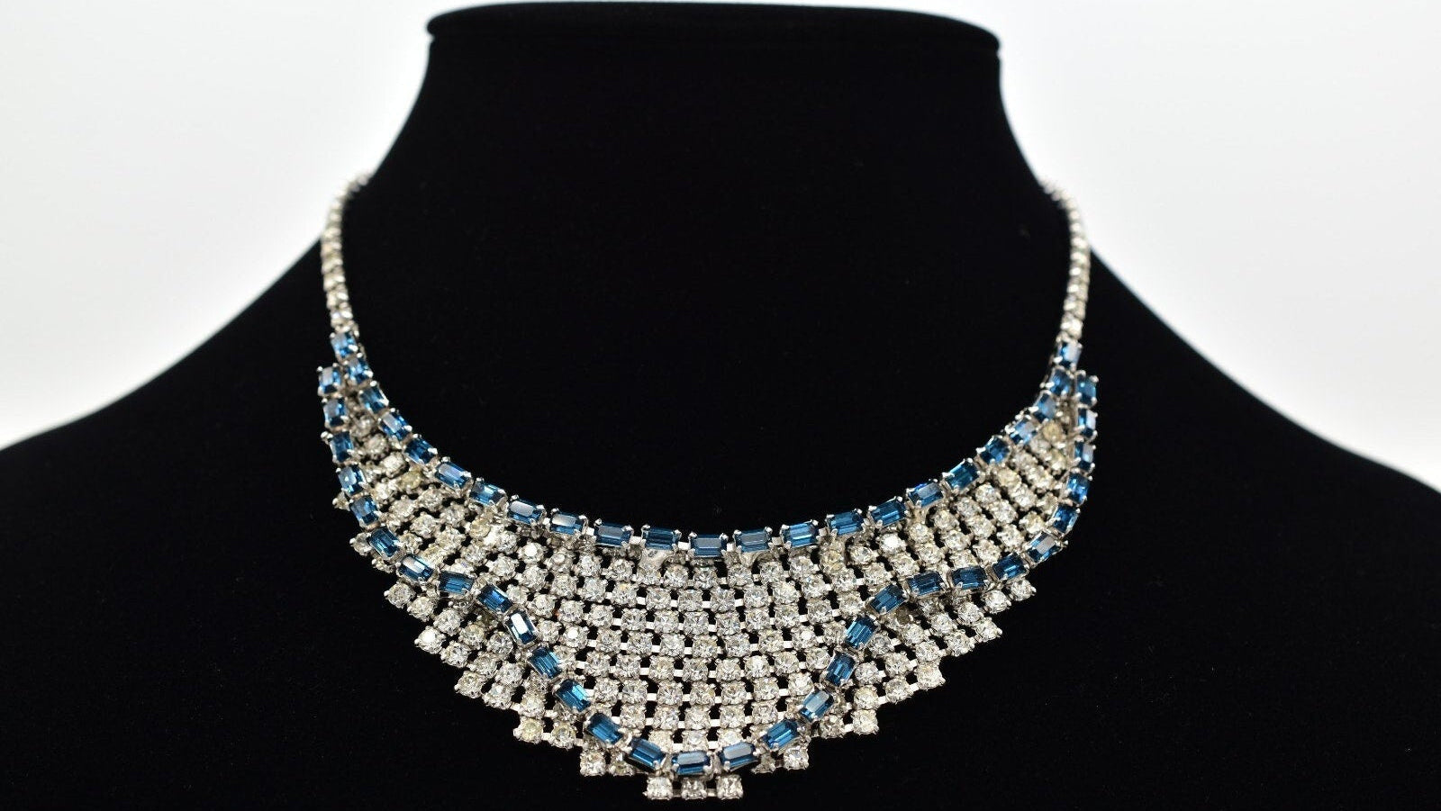 Elegant necklace with blue stones on a black mannequin against a white background