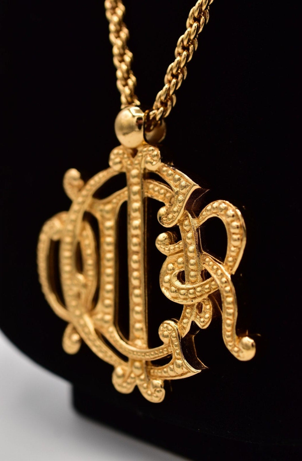 Gold monogram necklace on a black background