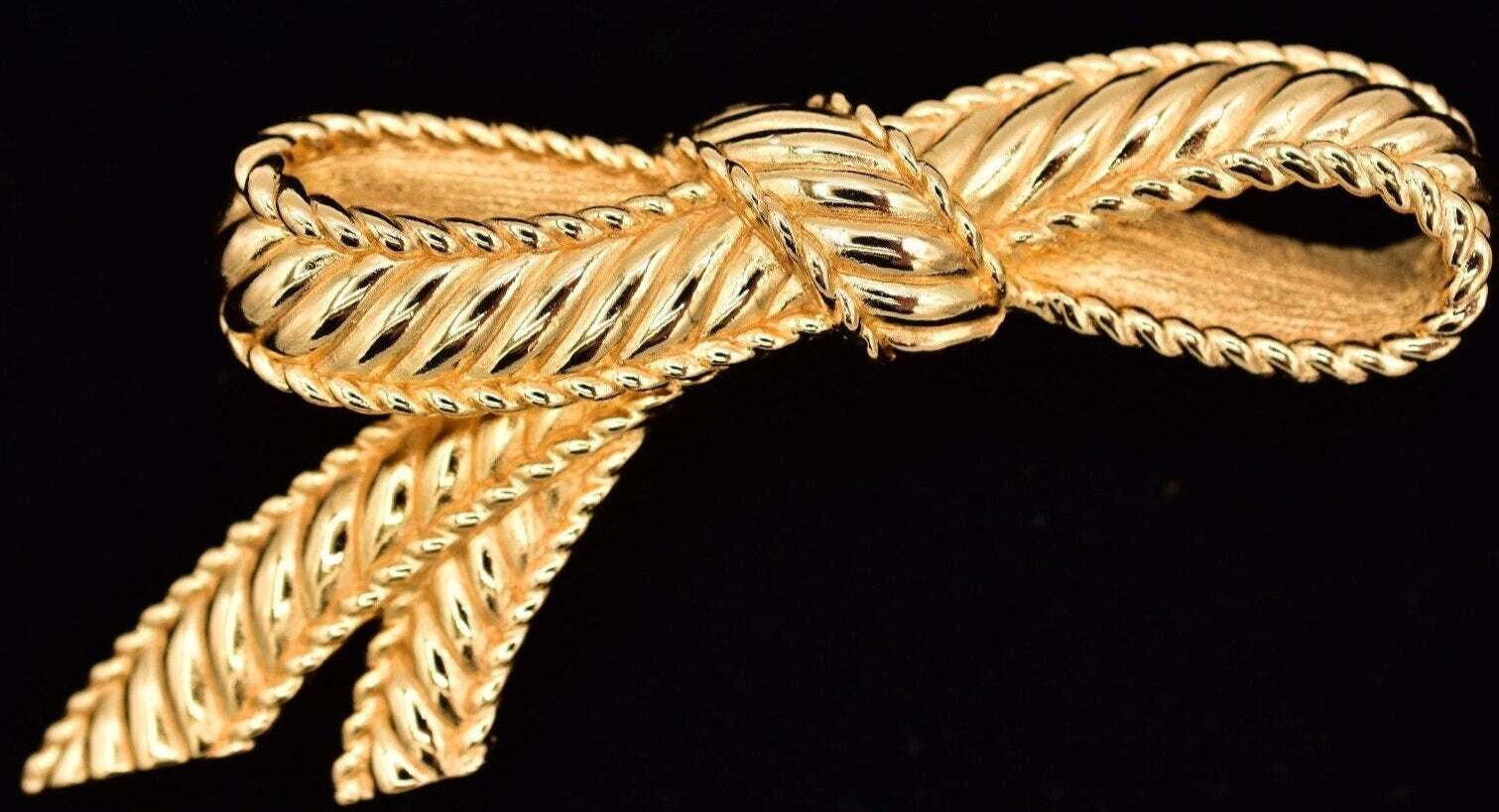 A vintage Christian Dior ribbed bow pin in polished gold.