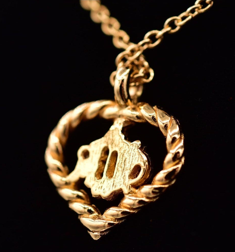 Gold necklace with a heart-shaped pendant on a black background