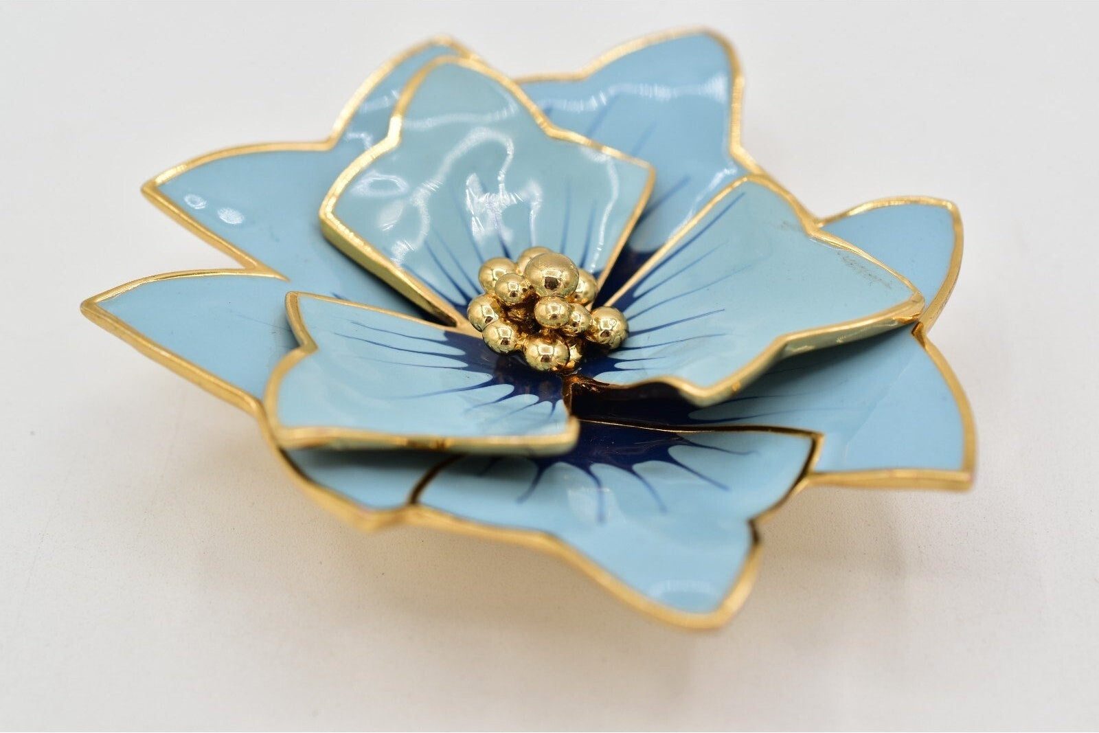 Blue flower-shaped object with gold accents on a white background