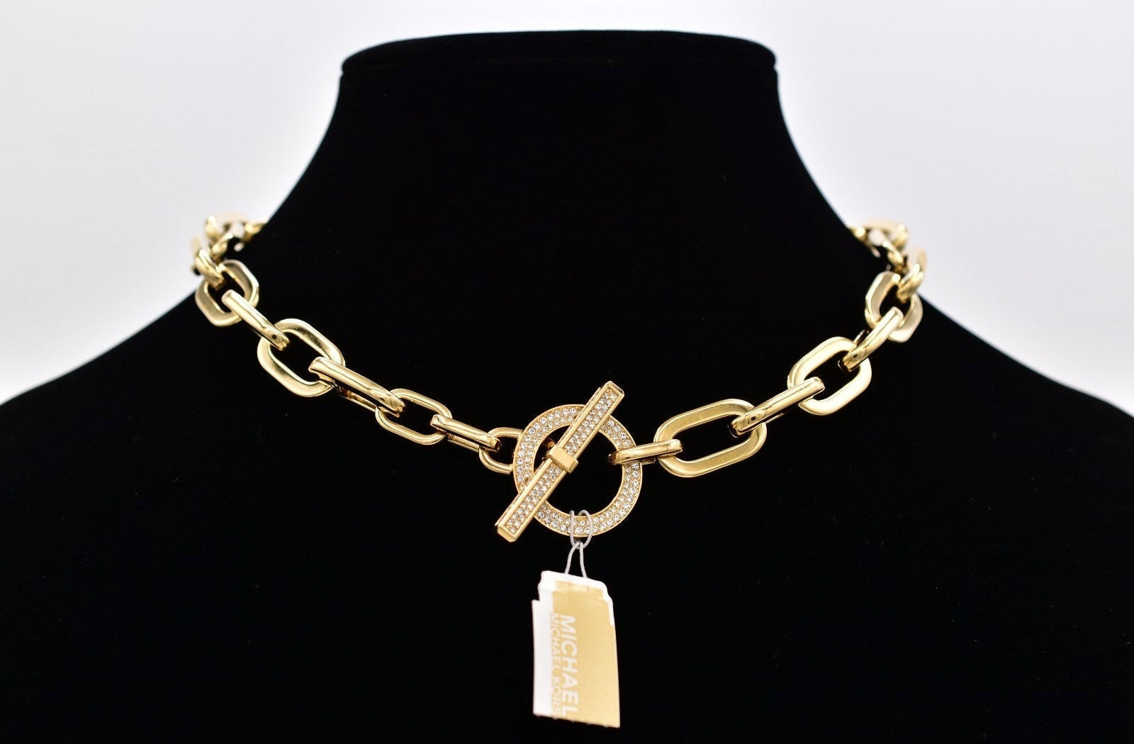 Gold chain necklace with a toggle pendant on a black mannequin against a white background