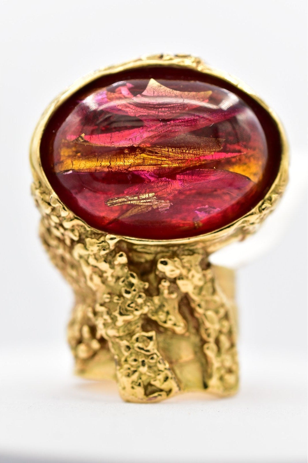 Gold ring with a red gemstone on a white background