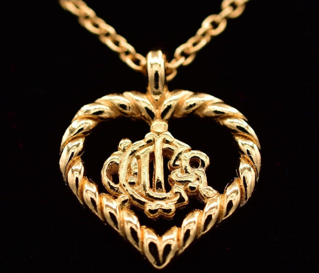 Gold heart-shaped pendant with intricate design on a black background