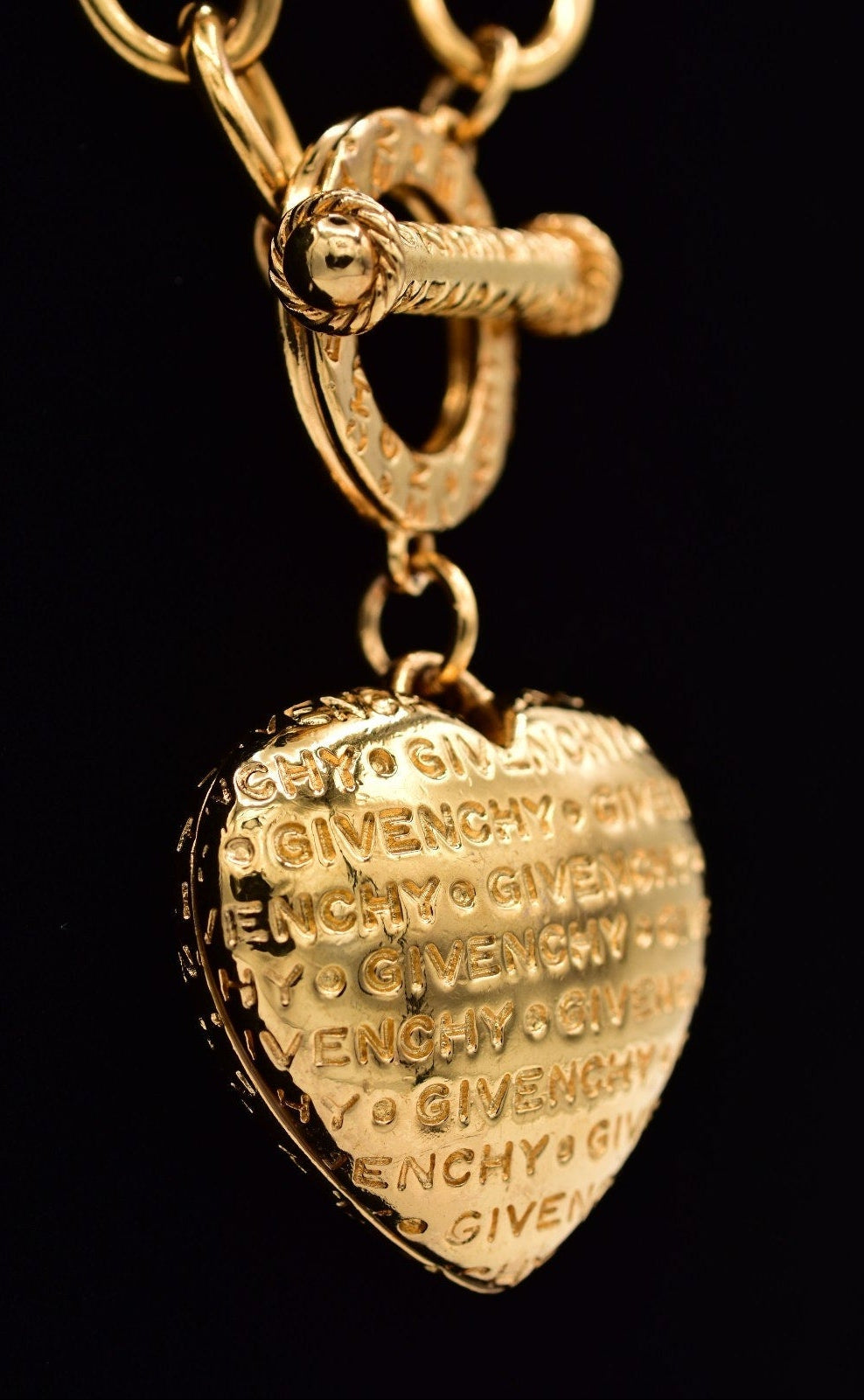 Gold heart-shaped Givenchy pendant on a black background