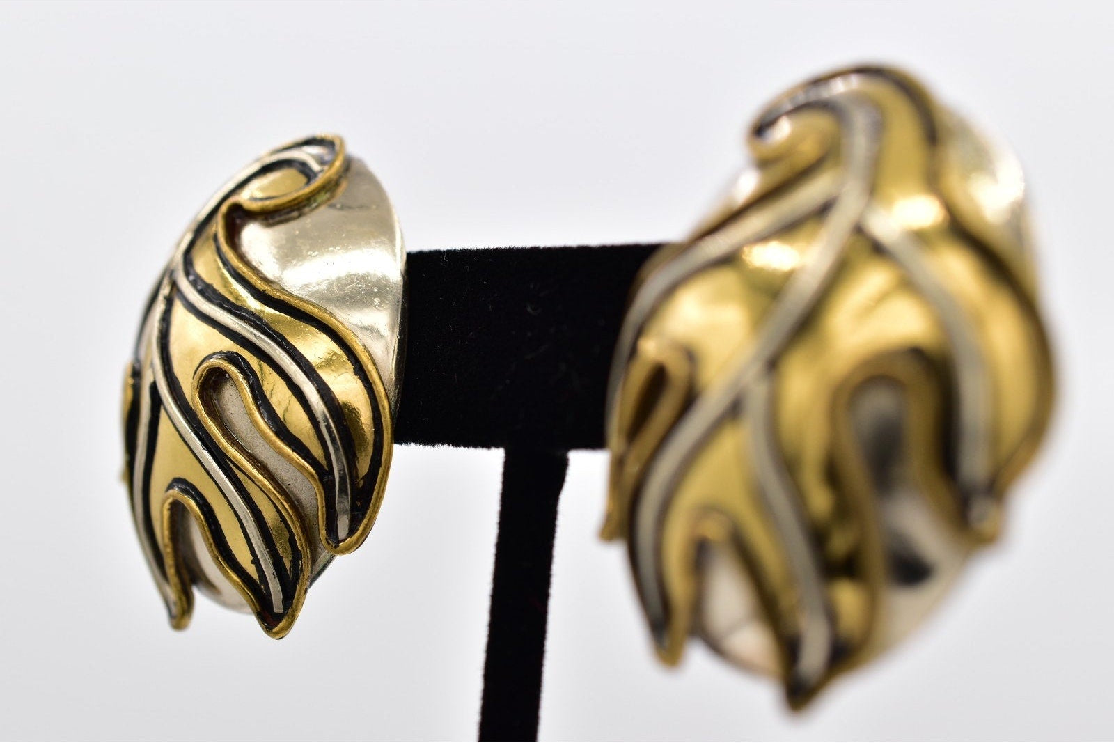 Gold and silver leaf-shaped earrings on a white background