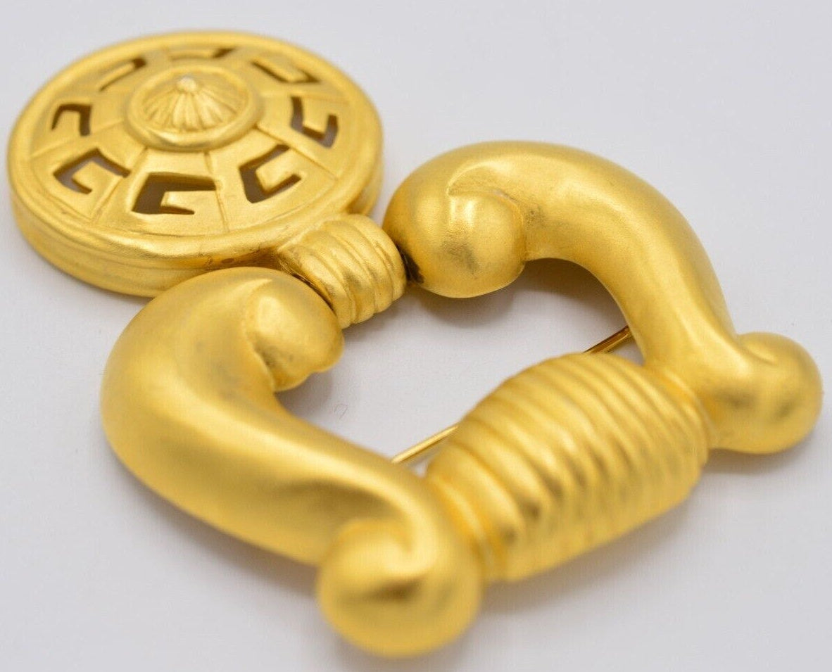 Angled view of a vintage Givenchy door knocker brooch on a white background
