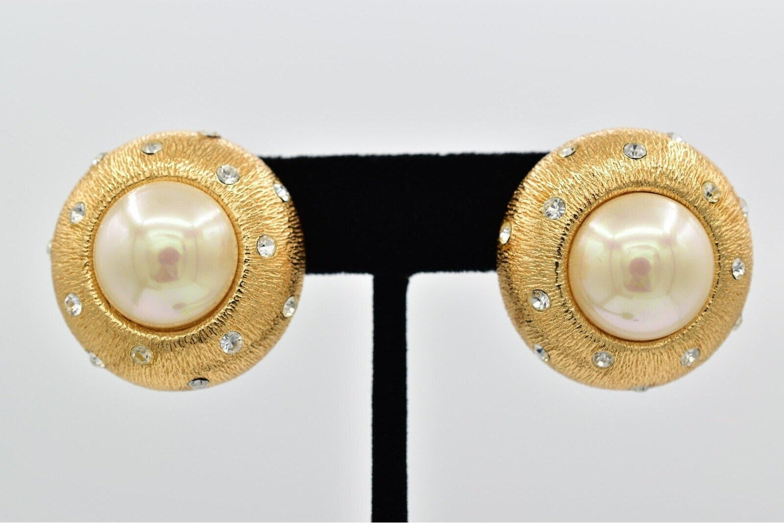Pair of gold earrings with pearl-like centers on a white background