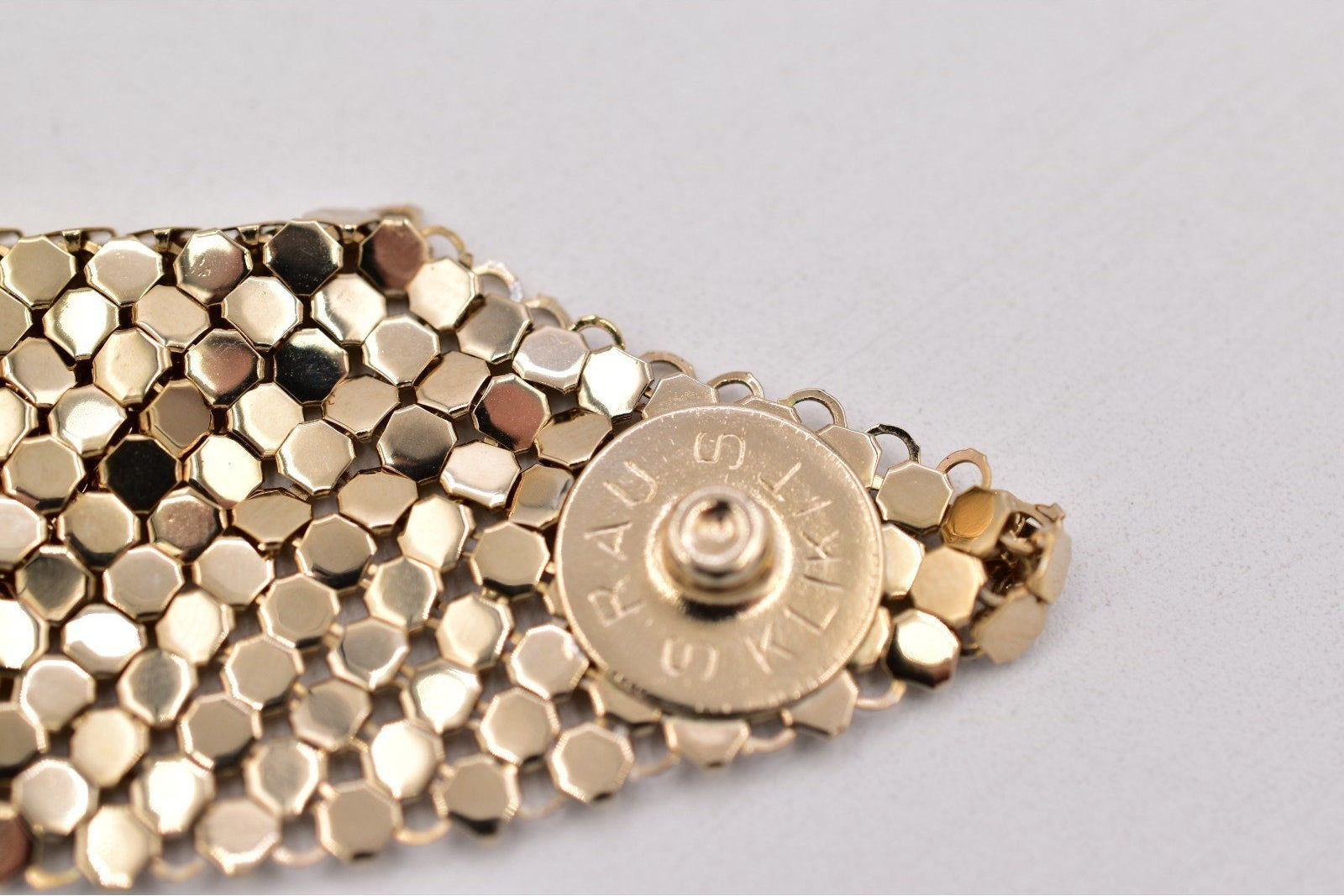 Gold bracelet with a hexagonal pattern on a light gray background