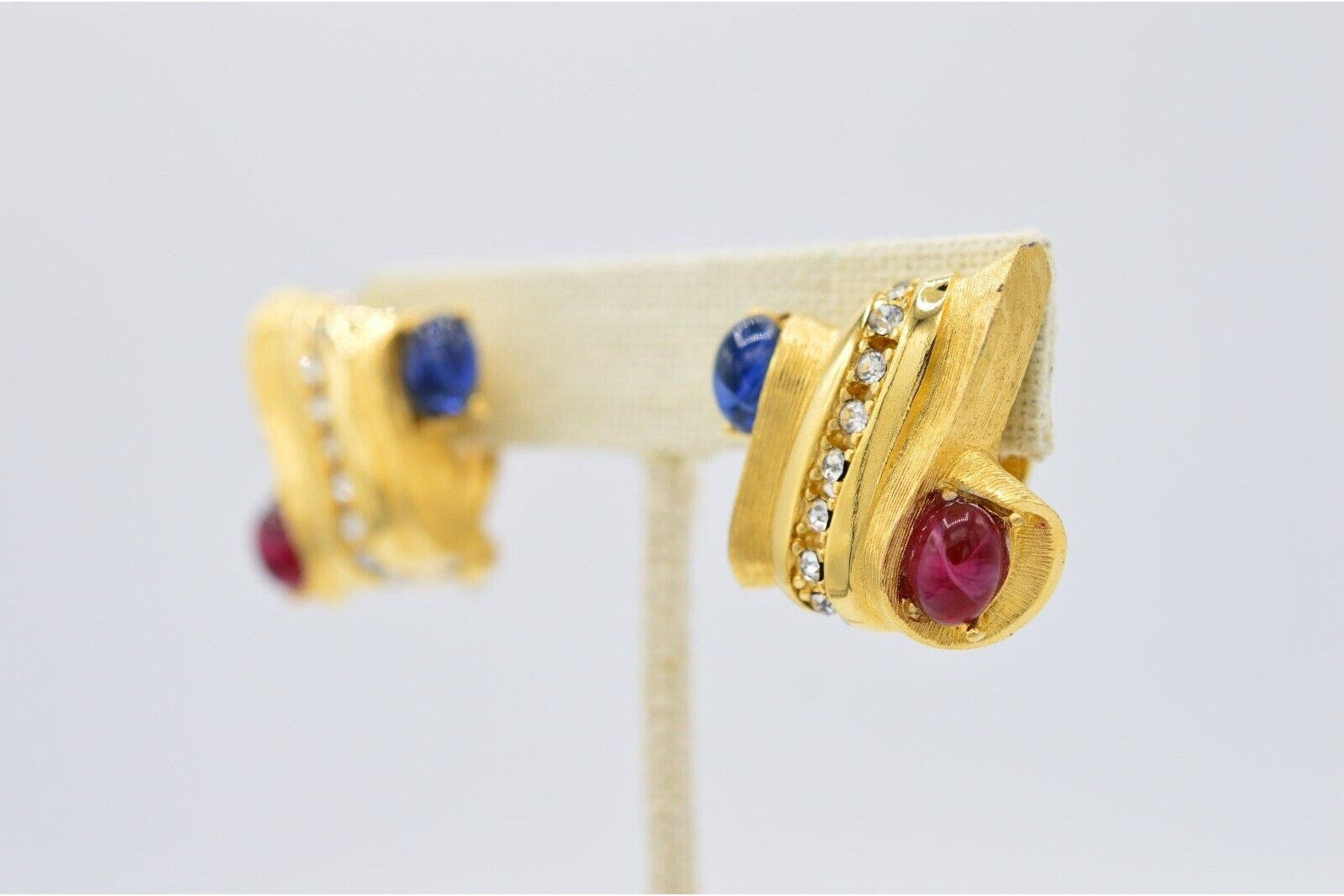 Gold earrings with gemstones on a light gray background