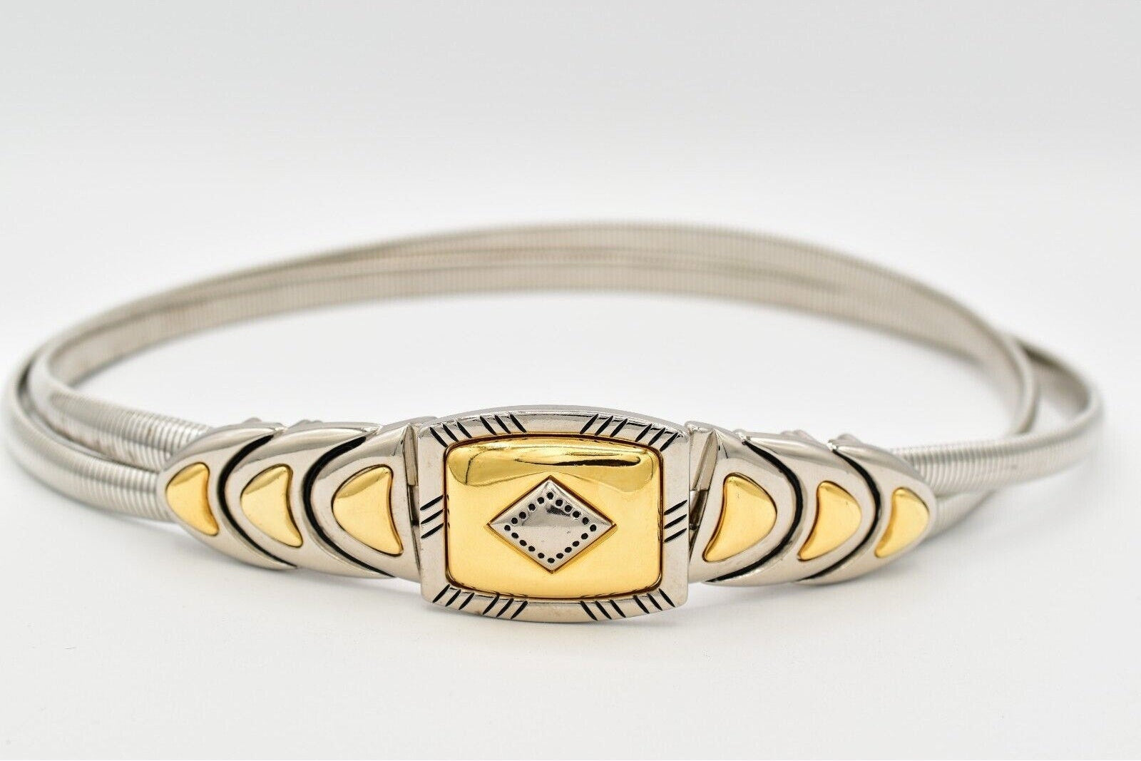 Gold belt with decorative buckle on a black dress against a white background