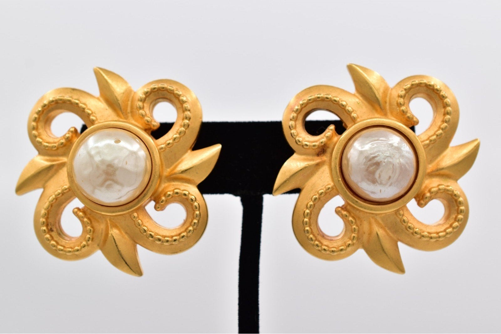 Pair of gold earrings with pearl centers on a white background