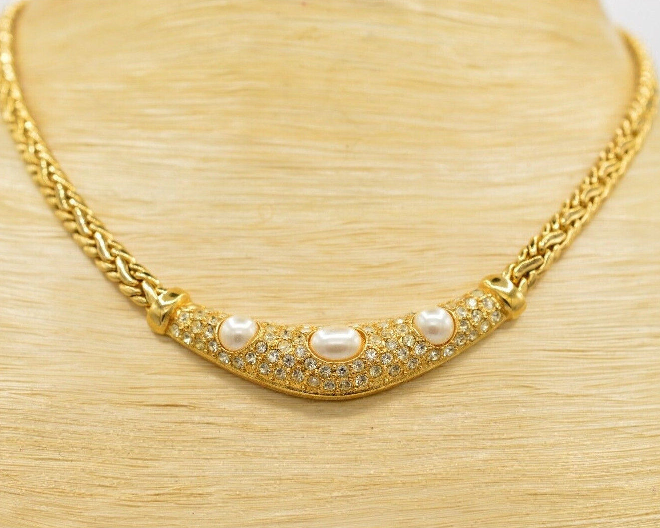 Gold necklace with pearls and crystals on a wooden surface