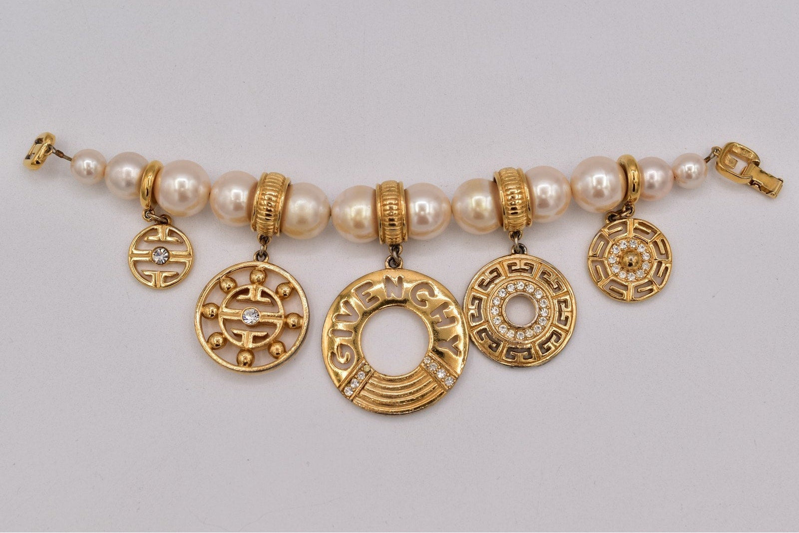 Bracelet with gold charms and pearls on a gray background